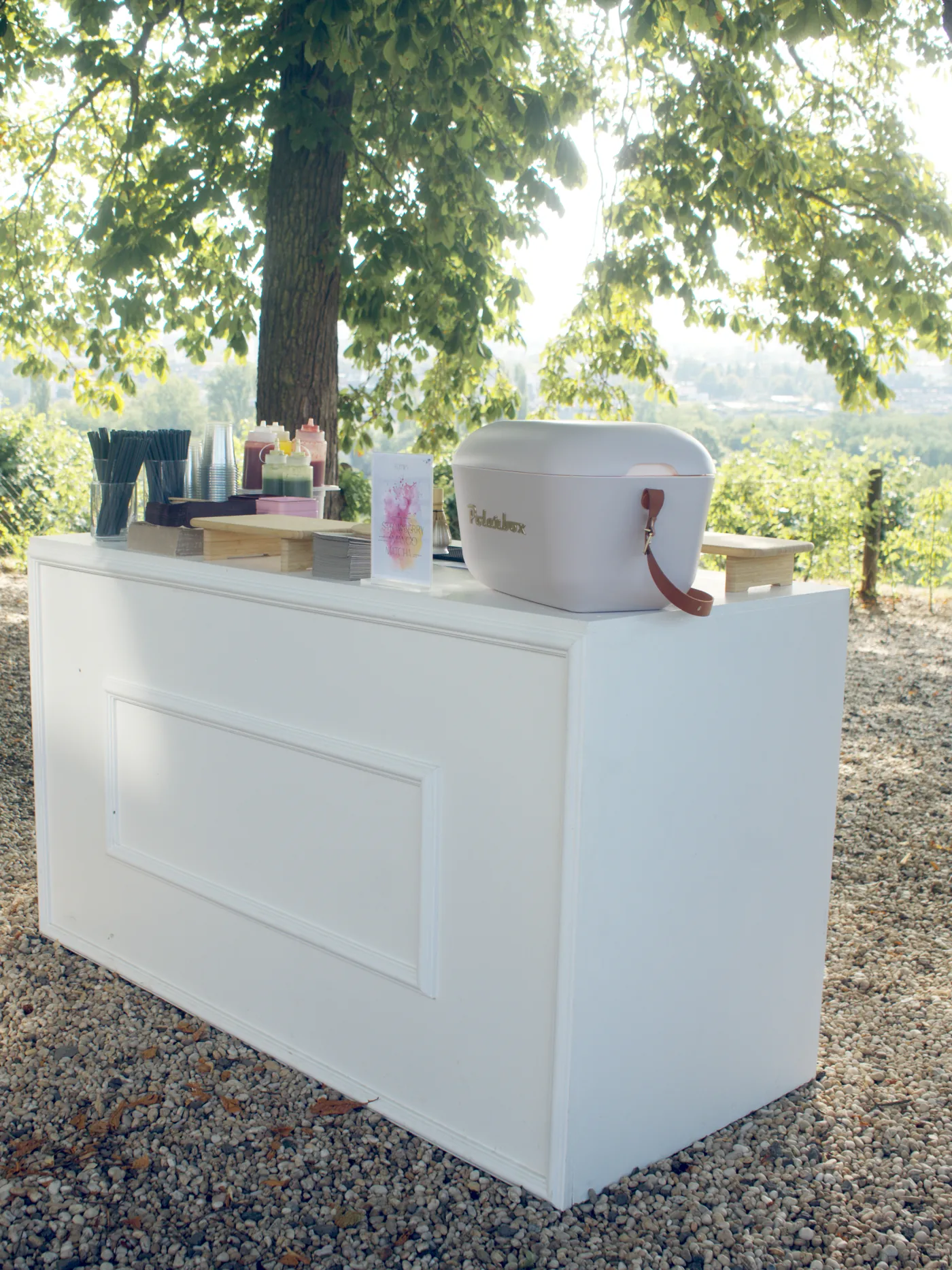 Die weiße mobile Femio Bar unter Bäumen mit Blick über die Weinberge