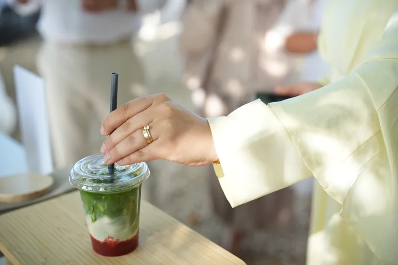 Ein Gast rührt seinen geschichteten Matcha Drink um