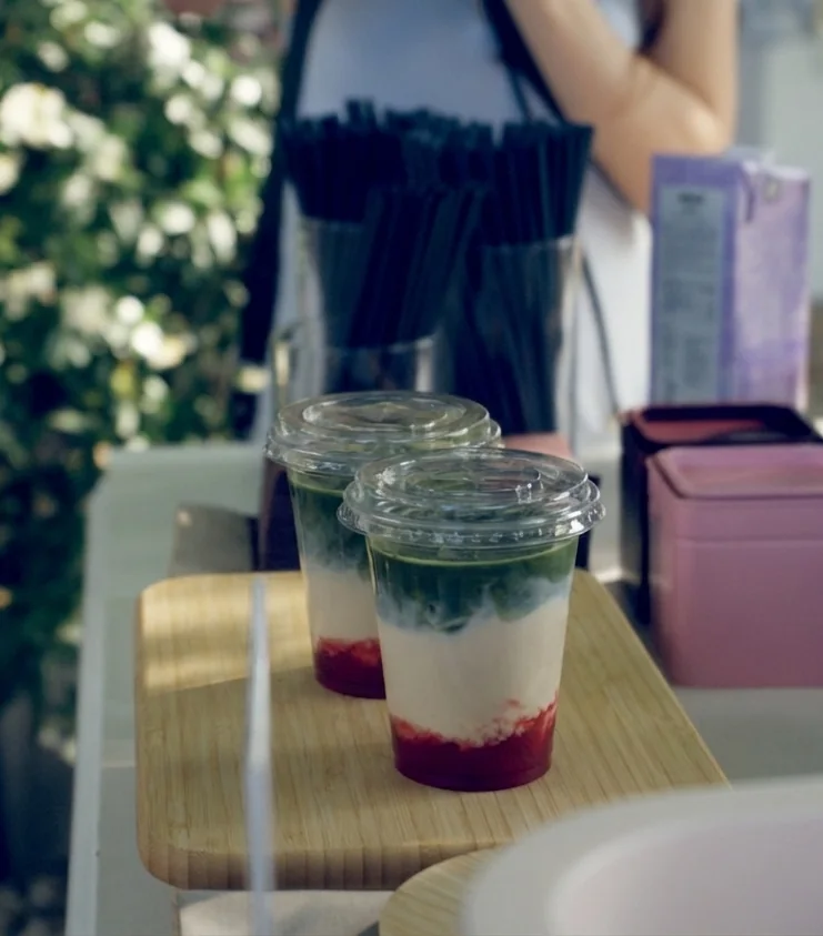 Zwei fertige Matcha Strawberry Drinks mit Deckel auf einem Holzbrett an der Femio Bar
